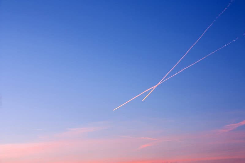 Aircraft condensation trails crossing a sky and spreading into thin cirrus