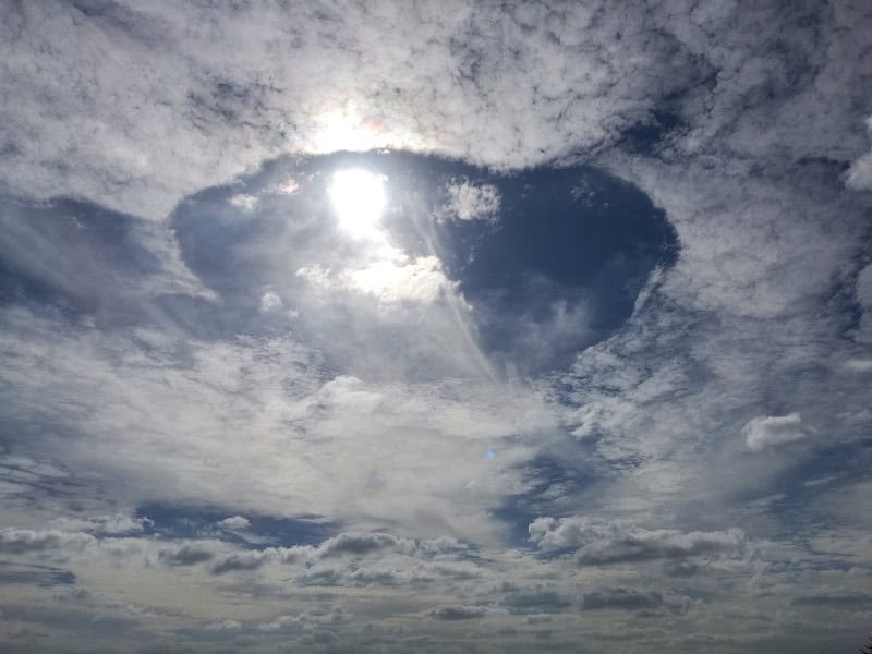 Large fallstreak hole punched through a cloud layer with ice streamers falling through the gap