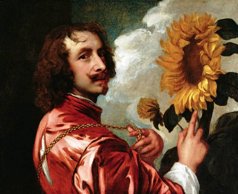 Long-haired young man in a red robe turning to look out of the frame, one hand lifting a heavy gold chain and the other gesturing towards a large open sunflower beside his head