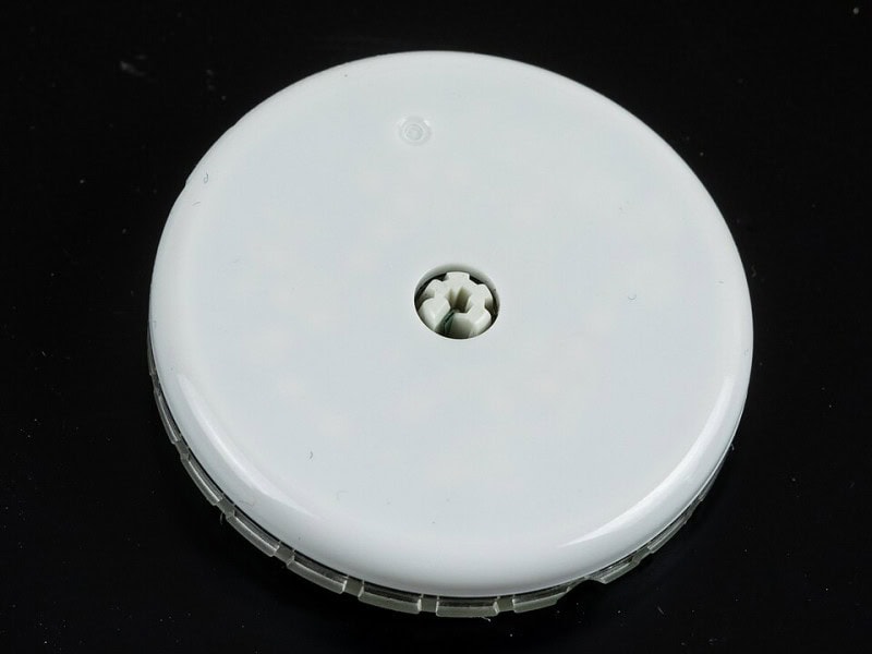 A round white Freestyle Libre glucose sensor photographed against a black background