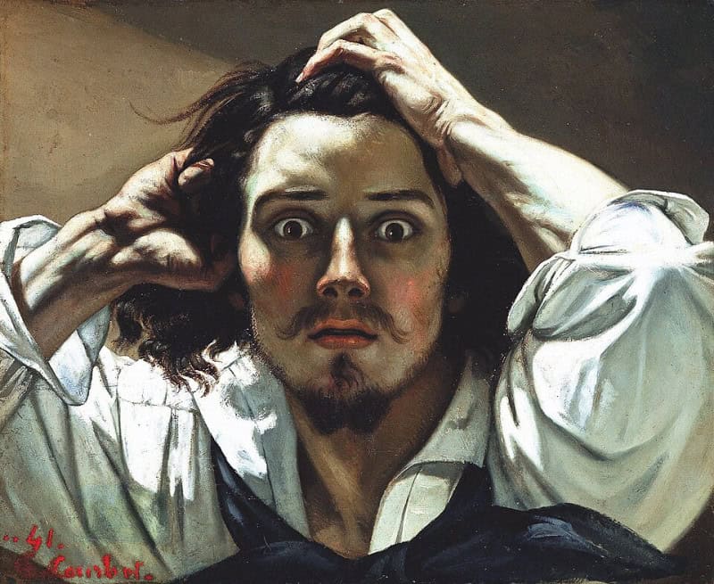 Young dark-haired man in a white shirt pressed close to the picture surface, both hands buried in his hair, eyes wide and staring straight out at the viewer
