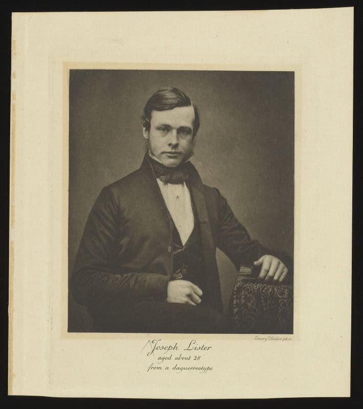 Sepia photogravure of a young Joseph Lister seated in a dark coat and bow tie, hand on a patterned chair back, captioned "Joseph Lister aged about 28"