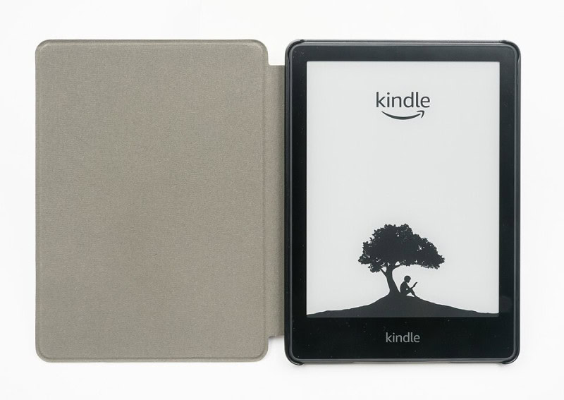 An Amazon Kindle Paperwhite e-reader in a folding cover, its e-ink screen showing a tree illustration