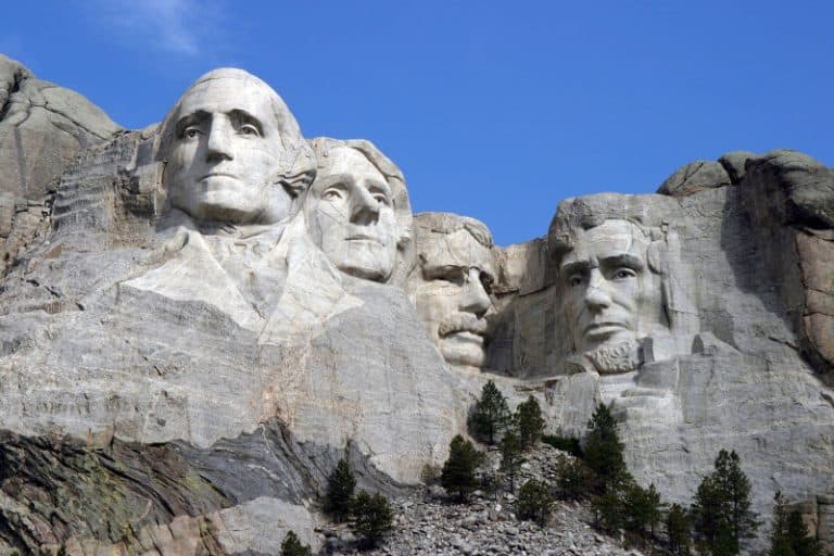 The four presidential heads of Mount Rushmore carved into a grey granite cliff face