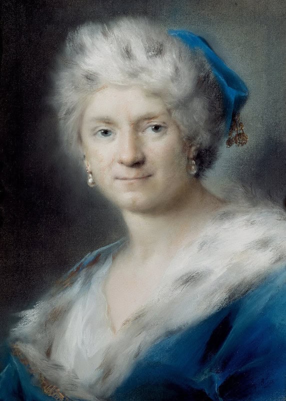 Pastel portrait of a woman in a tall white fur hat with a blue cap and gold tassel at one side, pearl drop earrings, and a white fur wrap over a blue gown, her face turned towards the viewer with a faint smile