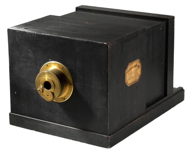 A Susse Frères daguerreotype camera: a black wooden sliding-box body with a brass lens barrel engraved "Daguerreotype" and a gold octagonal maker's label on the side