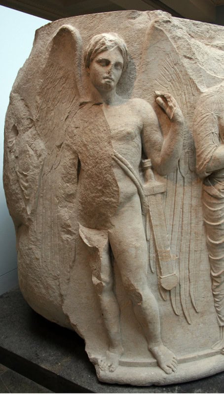 Winged nude youth carved on a curved marble column drum, a sword hanging at his side