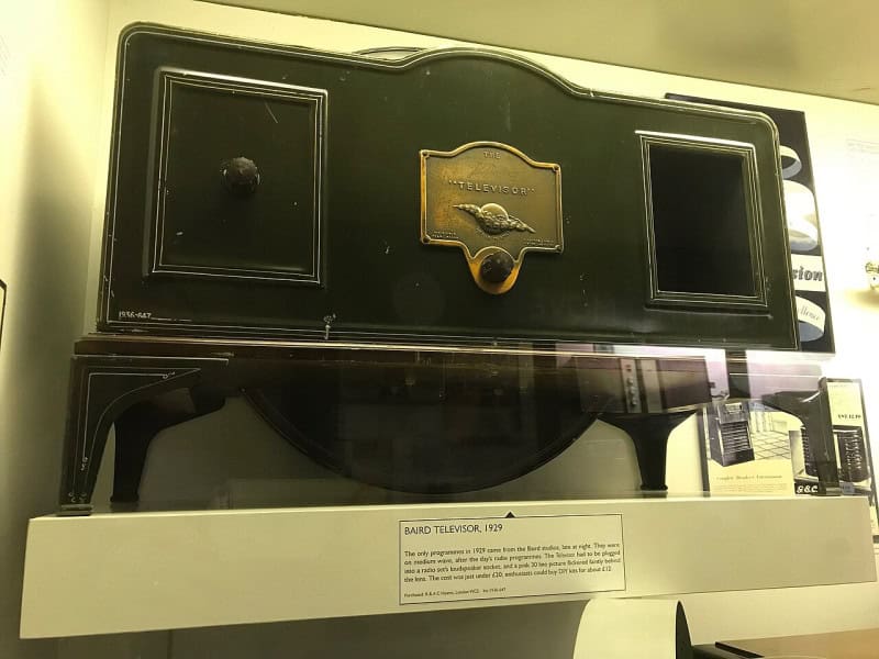 A 1929 Baird Televisor, a wooden cabinet with a small viewing window, in a museum