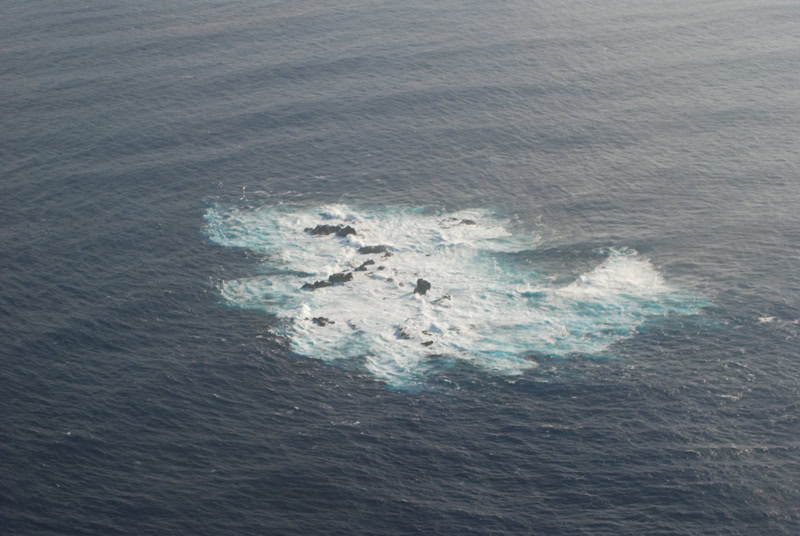 Aerial view of the Bayonnaise Rocks in grey-blue sea with white surf, photographed by the Japan Coast Guard in 2012