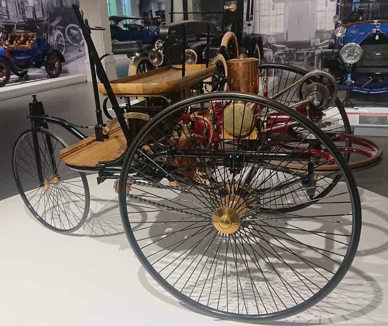 A replica of the Benz Patent-Motorwagen of 1886, a three-wheeled open carriage with a single-cylinder engine, in a museum
