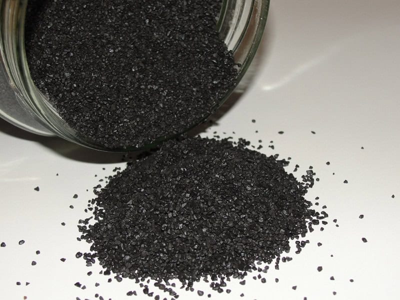 A pile of black-powder gunpowder grains spilling from a jar