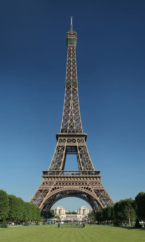 The Eiffel Tower in Paris, full length, seen from the Champ de Mars against a blue sky