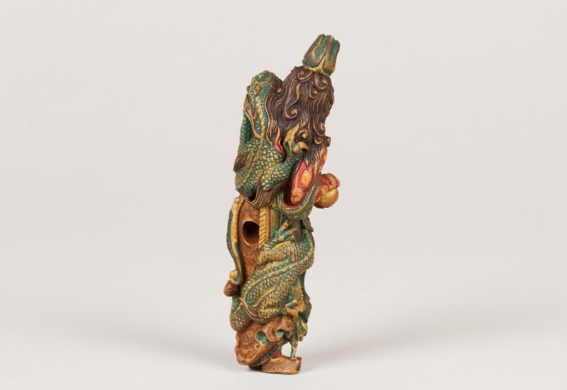 Carved and painted wooden netsuke of Ryujin, the dragon king of the sea, a bearded figure wrapped in a green dragon, in the Metropolitan Museum of Art