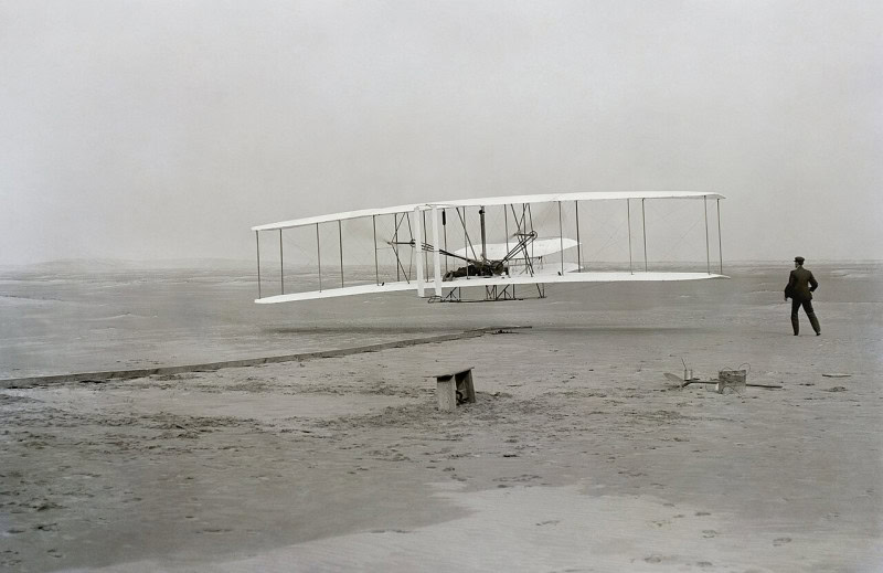 The Wright Flyer lifting off at Kitty Hawk on 17 December 1903 with Orville piloting and Wilbur running alongside