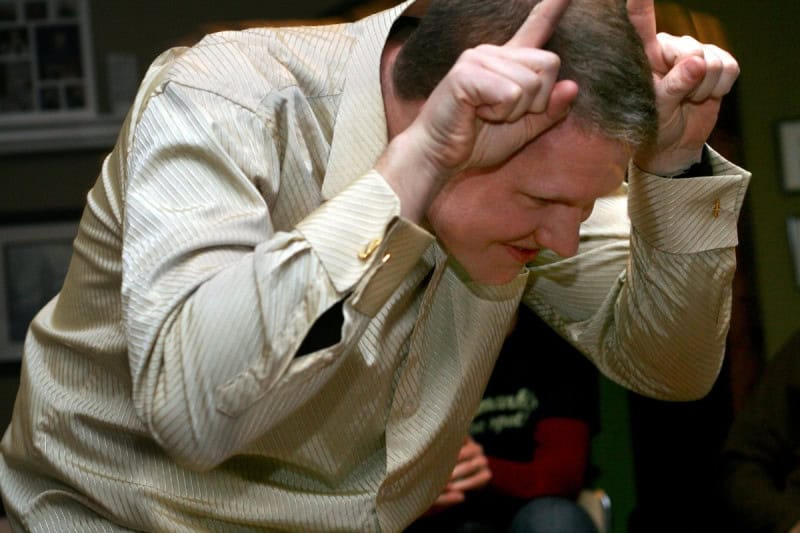A man acting out a word with both hands raised to his head during a game of charades