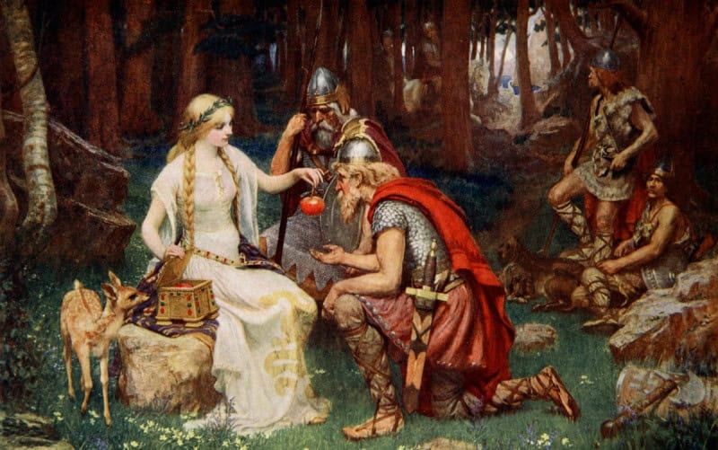 Idunn in a white gown holding out a golden apple to a group of gods gathered in a wooded clearing, in James Doyle Penrose's 1890 painting Idun and the Apples