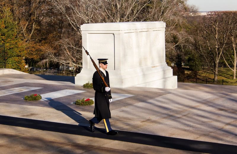 A sentinel of the Tomb Guard walking past the marble Tomb of the Unknown Soldier at Arlington National Cemetery