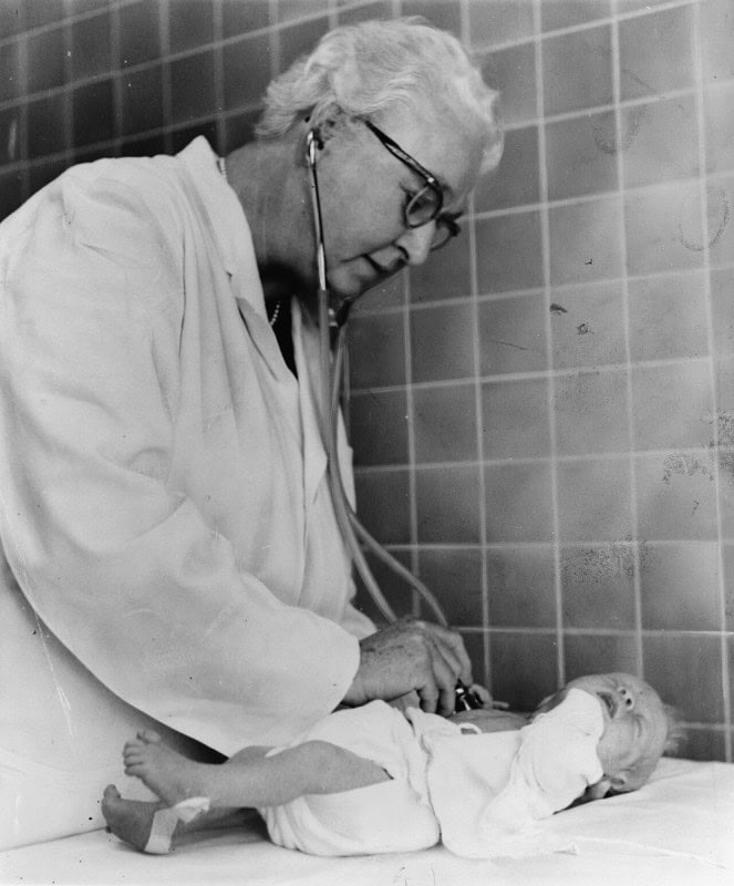 Virginia Apgar examining a newborn baby with a stethoscope